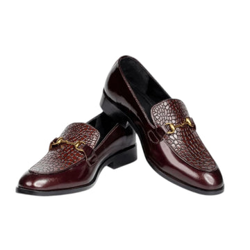 Pair of brown leather loafers with gold accents on a white background