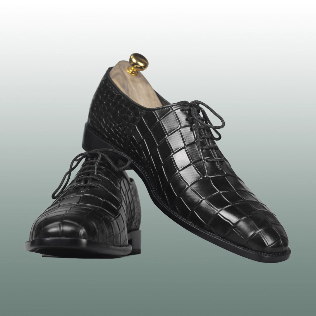 Pair of black dress shoes with a textured pattern on a light gray background