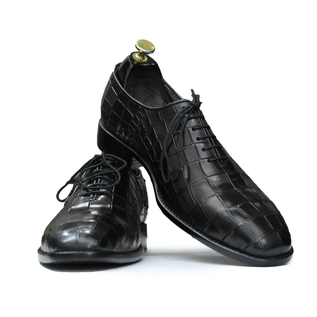 Pair of black dress shoes with a textured pattern on a white background