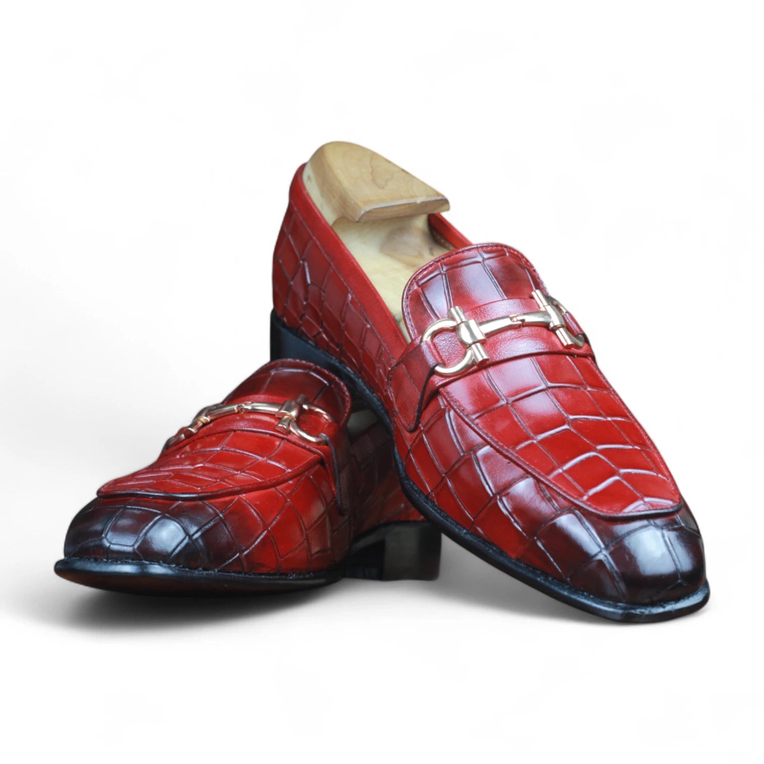 Red leather loafers with gold buckles on a white background