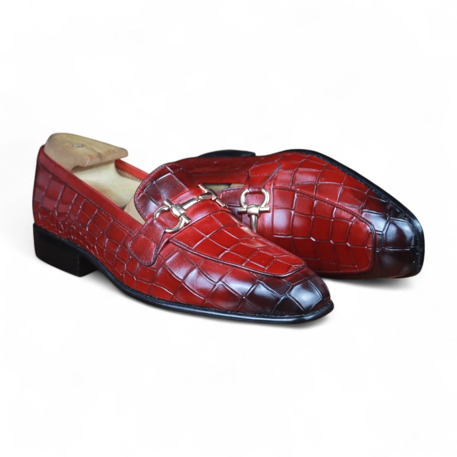 Pair of red leather loafers with a black toe cap on a white background