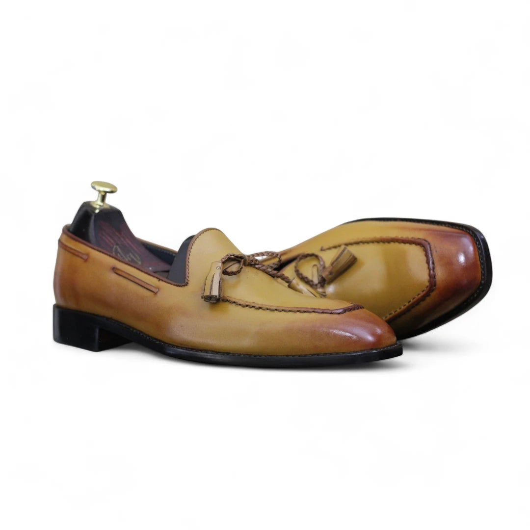 Pair of tan and brown leather loafers on a white background