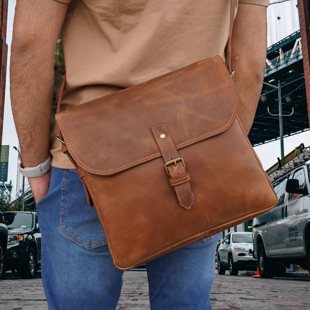 Person holding a brown leather bag in an urban setting