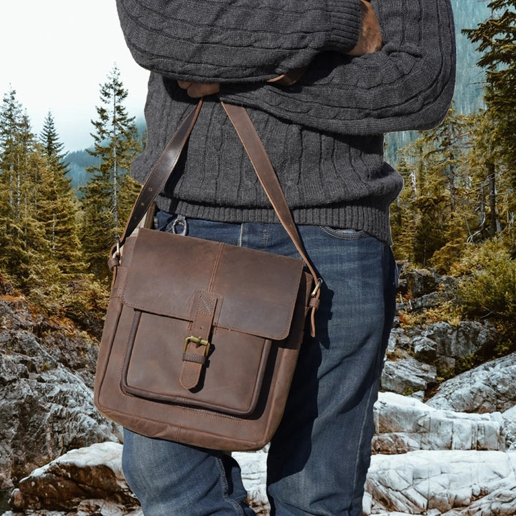 Person wearing a brown leather satchel bag in a forest setting Person holding a brown leather satchel bag outdoors