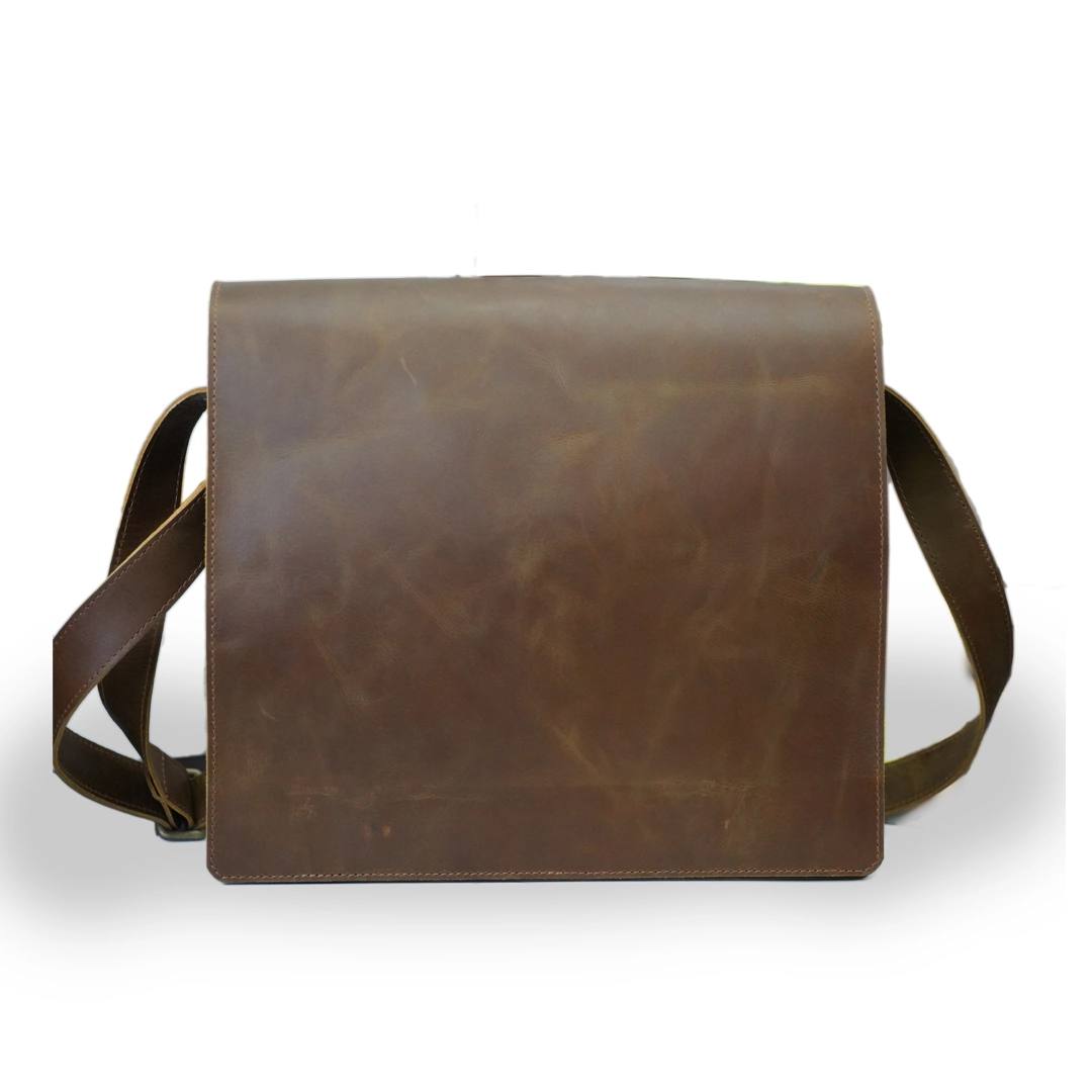 Front View – Close-up of the Adam Messenger Bag 2.0 showing the flap, buckle strap, and classic brown leather finish.