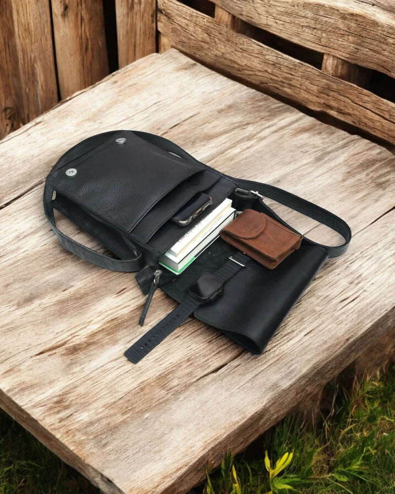 Back view of a black leather messenger bag with zippered pocket