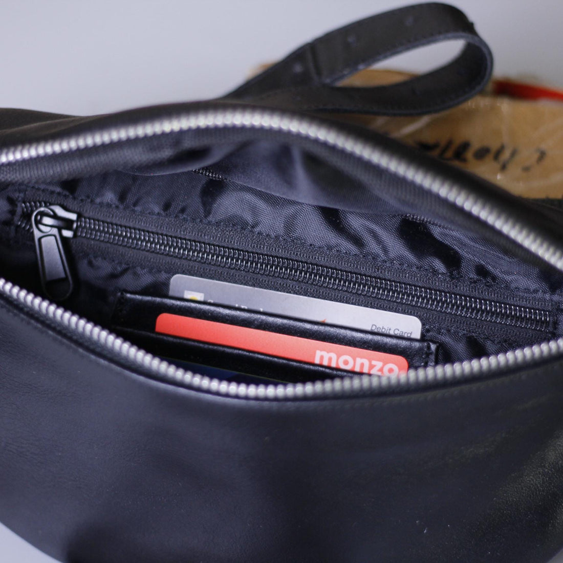 Front View – Stylish woven leather bumbag with sleek full-grain texture and front zip pocket.

